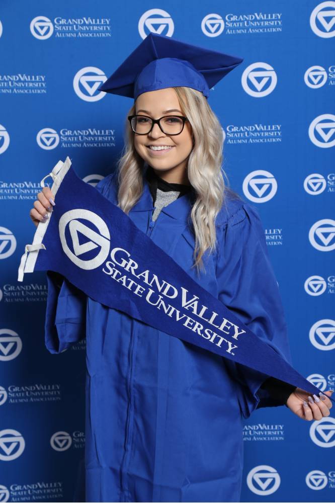Student poses with GV flag at Gradfest